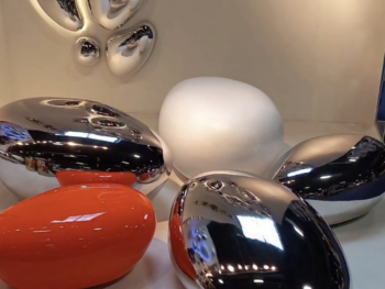 Composition de galets décoratifs Chrome Pebble Fuoriluogo Milano en finitions chrome miroir, blanc et orange, utilisés comme assises design au sol.